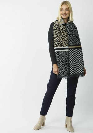Écharpe tricotée avec des motifs léopard et géométriques en noir, beige et gris ; finition avec des bords frangés.