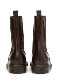 Bottines en cuir marron avec une finition lisse, des panneaux latéraux élastiques et des semelles plates. Elles présentent un logo discret sur le talon et des languettes de tirage.