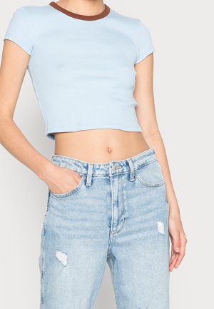Helles blaues, kurz geschnittenes T-Shirt mit einem braunen gerippten Ausschnitt, kombiniert mit ausgeblichenen, hoch taillierten Jeans aus Denim mit Abnutzungsspuren und einer lässigen Passform.