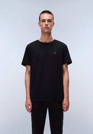 Zwarte katoenen t-shirt met korte mouwen, ronde hals en klein rood logo op de linkerborst. Draag het met zwarte cargo broeken.