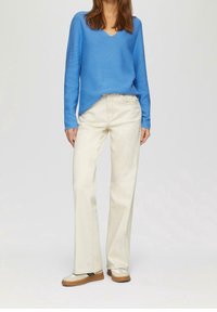 Ljusblå långärmad v-ringad tröja kombinerad med off-white vida jeans och beige sneakers med bruna detaljer.