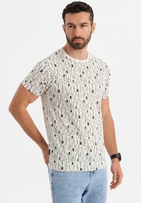 Camiseta blanca con estampado de texto negro en varias tipografías, de manga corta, cuello redondo y corte recto; combinada con jeans de color azul claro.