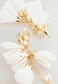 Gold flower stud earrings with white fabric petals, accented by gold hardware and small pearls, connected by a delicate chain.