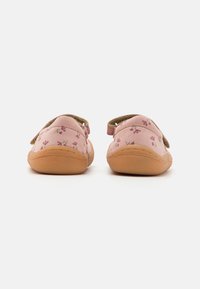 Rozā auduma kurpes ar ziedu rakstu, mīksta brūngana gumijas zole un regulējami velcro siksniņas. Apaļa forma, tekstila augšdaļa un mīkstināta iekšpuse.