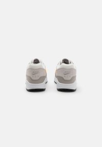 Hvide og grå Nike Air sneakers med en polstret mesh krave, struktureret overdel og en sort gummiydersål. Inkluderer præget logodetalje.