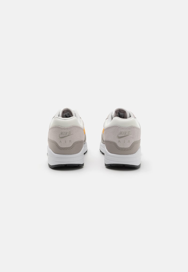 Zapatillas Nike Air en blanco y gris con un collar acolchado de malla, parte superior texturizada y una suela exterior de goma negra. Incluye detalles del logo en relieve.