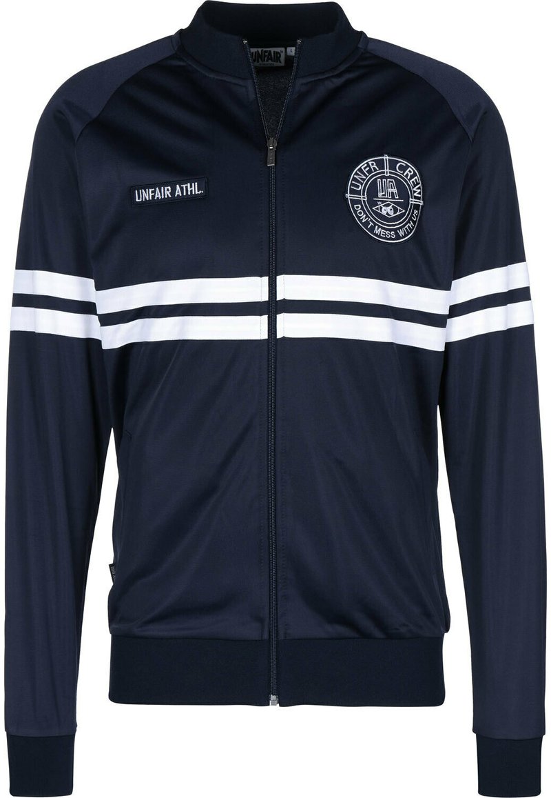 Veste de survêtement bleu marine en polyester lisse avec des rayures blanches sur les manches. Présente un zip à l'avant, un col montant et un logo brodé sur la poitrine.
