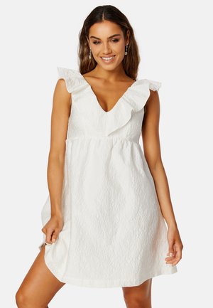 Robe blanche en tissu texturé, décolleté en V et accents d'épaule à volants, avec une coupe décontractée et une longueur au genou.