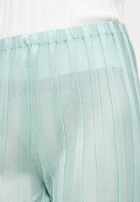 Ελαφριά, διαφανή παντελόνια με κάθετες ρίγες σε απόχρωση μέντας, με υφαντή υφή και ελαστική μέση, εμφανίζοντας σχεδιασμό με στρώσεις.