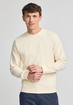 Sudadera color crema con el texto en relieve "POLO CLUB". Presenta un cuello redondo y puños de canalé, elaborada con una tela suave y texturizada.
