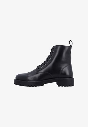 Zwarte leren enkellaars met veters aan de voorkant, treklusje bij de hiel, dikke grof profiel zool en ronde neus, zijaanzicht op een witte achtergrond.