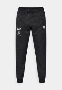 Μαύρο παντελόνι jogger με γεωμετρικό σχέδιο, ελαστική μέση, ρυθμιζόμενο κορδόνι και λευκά τυπωμένα λογότυπα στο αριστερό μηρό.