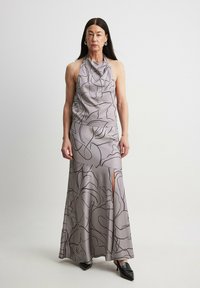 Halter-neck, floor-length dress in light gray satin with black floral outlines. Features flowing fabric, side slit, and minimalistic design.