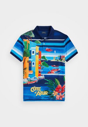 Korte mouw polo in het blauw met kleurrijke strepen en een levendig kustlandschap, met boten en kleurrijke gebouwen. Katoenen stof.