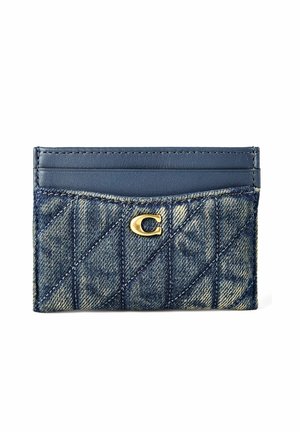 Porte-cartes en cuir denim et bleu marine avec motif matelassé et logo métallique doré "C" sur le devant, disposant de trois emplacements pour cartes.