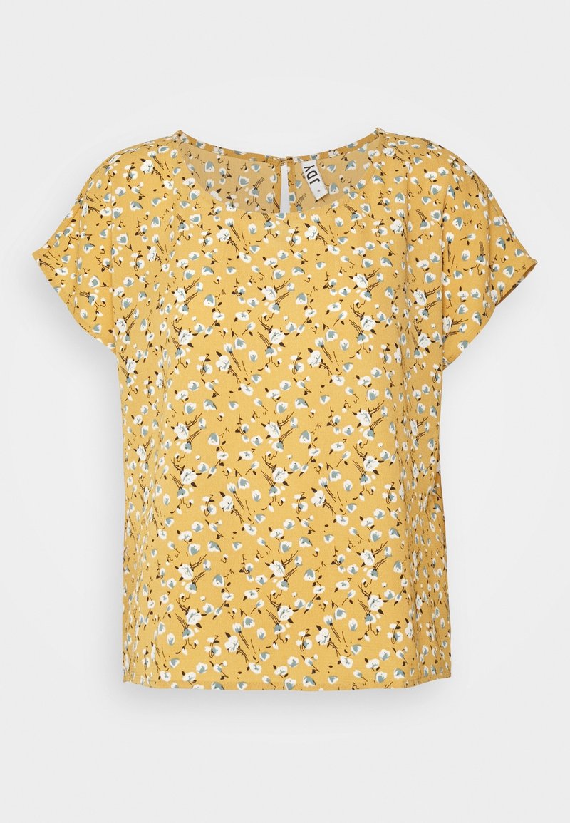 Blouse jaune à manches courtes avec motif floral blanc et bleu et col rond sur fond uni.