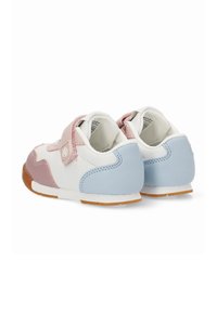 Zapatillas blancas para bebé con detalles en rosa y azul, correas de velcro y suelas marrón claro, vistas desde la parte trasera sobre un fondo blanco.