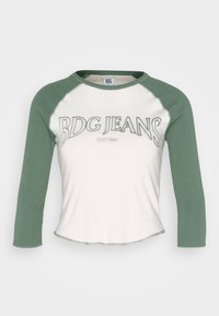 Zelené a bílé baseballové tričko s tříčtvrtečními rukávy; obsahuje grafiku "BDG JEANS" a detail "EST 1998". Měkká bavlněná tkanina, kulatý spodní lem.