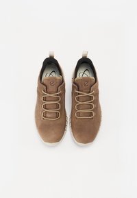 Barna velúr sneaker, texturált felülettel, bézs fűzőkkel és húzófüllel, fehér gumitalppal és fekete bélés belsővel.