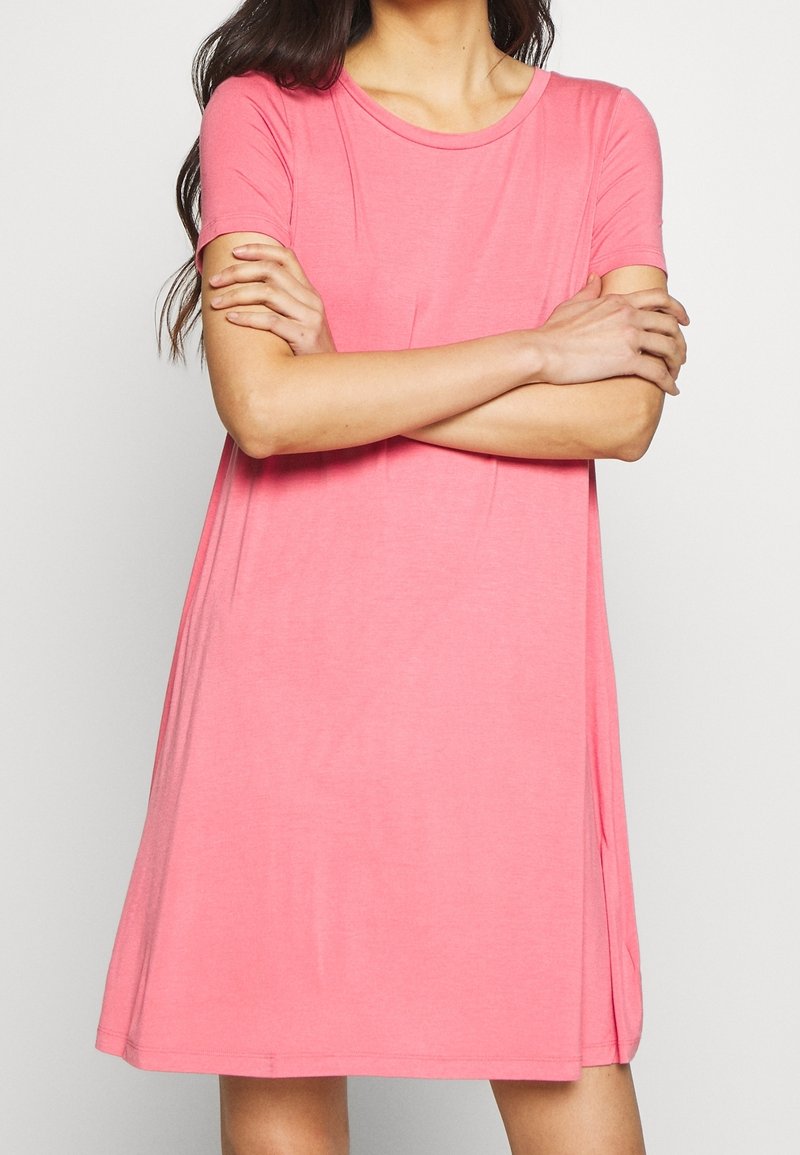 Krátký rukáv, šaty po kolena z jemné, lehké růžové látky, s kulatým výstřihem a bočními rozparky pro snadný pohyb.
