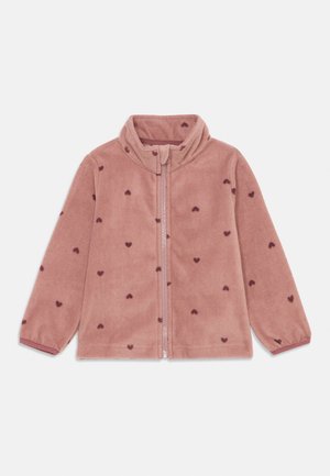 Veste en polaire rose clair avec un col haut, présentant de petits motifs en forme de cœur rose foncé et une fermeture éclair à l'avant. Texture douce et manches longues.