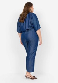 Mörkblå, lättvikts jumpsuit i tyg med korta ärmar, elastisk midja och smalnande ben. Bärs med klackskor i djurmönster.