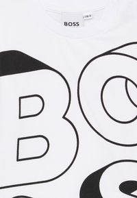 Bijela majica s odvažnim crnim natpisom "BOSS". Ima okrugli izrez i mekanu teksturu tkanine. Minimalistički dizajn bez dodatnih uzoraka.