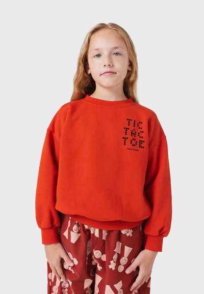 Rode sweatshirt met lange mouwen, geribbelde manchetten en een ronde halslijn. Voorzien van zwarte grafische tekst op de voorkant. Patroonbroek daaronder.