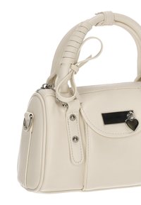 Bolso sintético blanco con diseño curvo, asa texturizada, herrajes en tono plateado y un charm en forma de corazón. Cuenta con un bolsillo frontal.