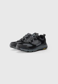 Pair of black and gray athletic sneakers with lace-up closure, branded logo on sides, and thick rubber soles with yellow Goodyear branding.
