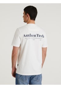 Bijela pamučna majica s velikim tamnoplavljim printom na leđima na kojem piše "AuthenTech". Kratki rukavi i klasičan dizajn s okruglim izrezom.