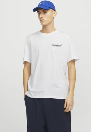 Bílý bavlněný tričko s krátkými rukávy, na levé části hrudníku je námořnické script logo "Originals Since 1900". Spárováno s tmavými strukturovanými kalhotami.