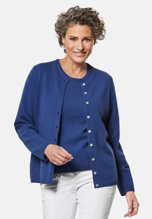 Koninginblauwe cardigan van zacht materiaal, met een ronde halslijn, lange mouwen en knoopsluiting met contrasterende knopen.