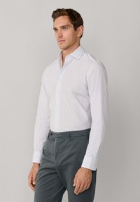 Witte button-up shirt met een ruitpatroon, lange mouwen en knoopsluiting bij de manchetten, gecombineerd met grijze pantalon. Gladde textuur engetailleerde pasvorm.