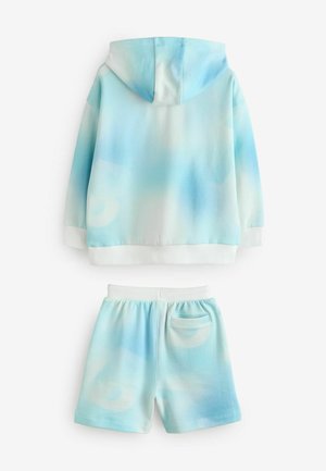 Ensemble de sweat à capuche et de shorts en tissu dégradé bleu clair, présentant une texture douce, des finitions blanches et une poche arrière sur les shorts.