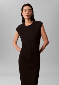 Svart ärmlös klänning med rund halsringning, figurnära silhuett och slät tygstruktur. Inga synliga mönster eller utsmyckningar.