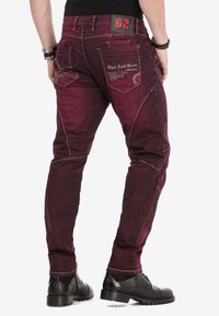 Bordeaux skinny-fit jeans met decoratieve stiksels, schuine zijzakken en logo-accenten op de achterzak en de tailleband.