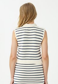 Mouwloze top met een crèmekleurige basis en marineblauwe horizontale strepen, een gestructureerde band bij de taille en een kraagdetail.