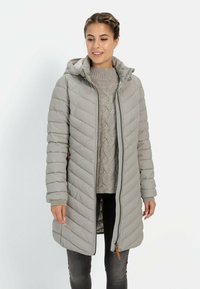 Grijze gewatteerde jas met een capuchon, voorzien van een diagonaal quiltpatroon, zijvakjes en een rits over de volledige lengte. Draagt over een lichtgebreide trui.