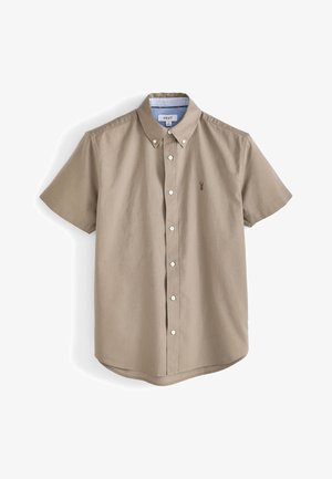 Kortärmad, kragad skjorta i beige bomull. Har vita knappar, en liten broderad logotyp och en randig innerkrage. Rundad nederkant.