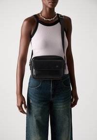 Borsa a spalla in pelle nera con forma rettangolare, tasca frontale con zip e tracolla regolabile. Design semplice con dettagli del logo.