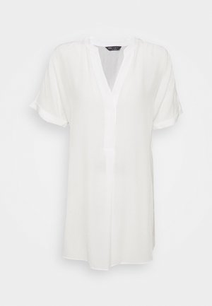 Biała tunikowa bluzka z krótkim rękawem, dekoltem w serek i luźnym krojem, wykonana z lekkiego materiału.