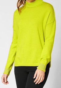 Helle gelbe Strickjacke mit hohem Kragen, lässiger Passform, tief angesetzten Schultern und gerippten Akzenten an den Bündchen und dem Saum.