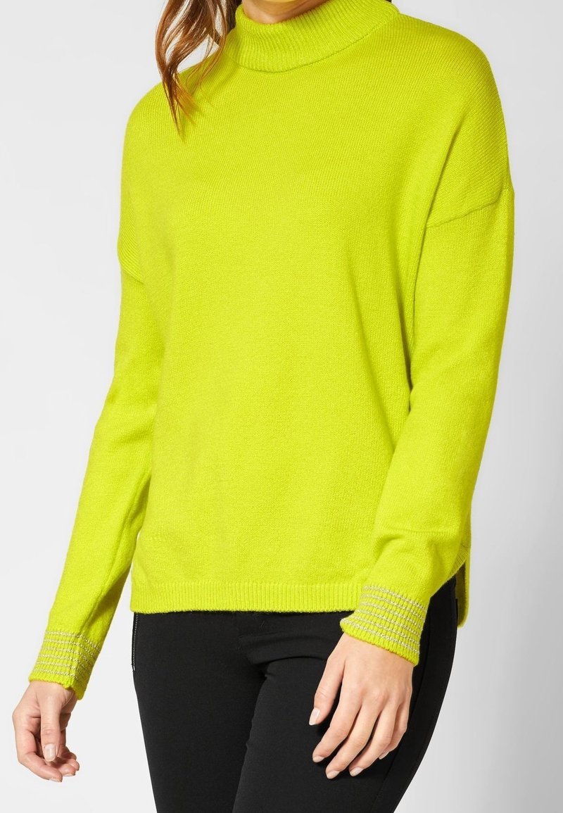 Helle gelbe Strickjacke mit hohem Kragen, lässiger Passform, tief angesetzten Schultern und gerippten Akzenten an den Bündchen und dem Saum.