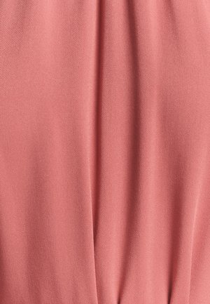 Blødt, tekstureret stof i en lys koralfarve, der har et glat, draperet udseende med en subtil diagonalt vævemønster.