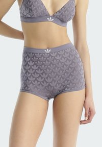 Šedá sportovní podprsenka a vysoké kalhotky s listovým vzorem a kontrastním bílým logem na pásku a na podprsence.