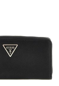 Portefeuille noir texturé avec fermeture éclair, arborant un emblème triangulaire en métal argenté avec "GUESS USA." Matériau extérieur lisse avec des accents minimaux.