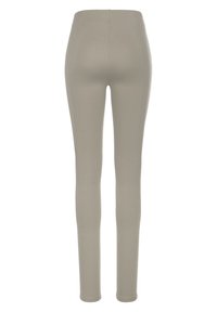 Světle béžové legíny vyrobené z elastického materiálu, s vysokým pasem a přiléhavým střihem, hladká textura bez viditelných švů.