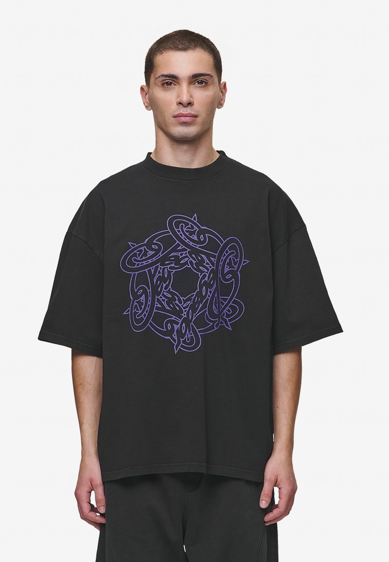 Black oversized t-shirt made of cotton, featuring a central purple graphic design with intertwining shapes and patterns. Short sleeves, crew neck.