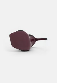 Sunglasses with a large, angular burgundy frame featuring vertical stripes. The temples are sleek with a smooth finish, and there’s a soft interior lining.